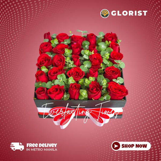 Elegant gift box containing a stunning arrangement of 25 red roses, complemented by delicate eucalyptus fillers and adorned with a luxurious red and white satin ribbon.