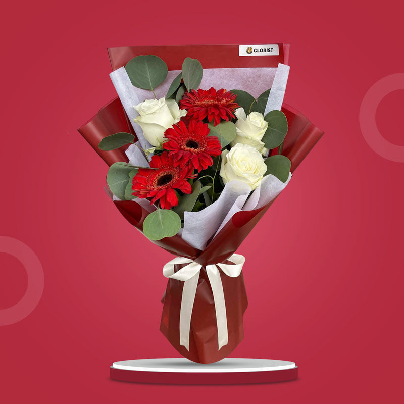Abundant Love bouquet with red gerberas, white roses, and eucalyptus in maroon and white wrap with cream ribbon