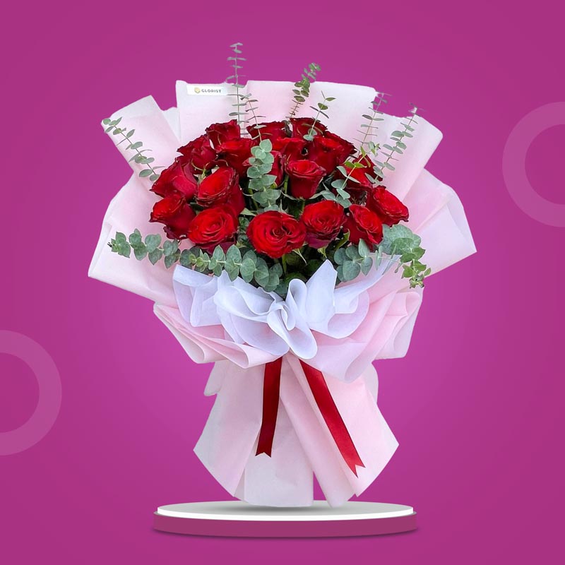 Alluring Flora bouquet with 20 red China roses and eucalyptus baby blue in light pink and white wrap tied with a maroon ribbon
