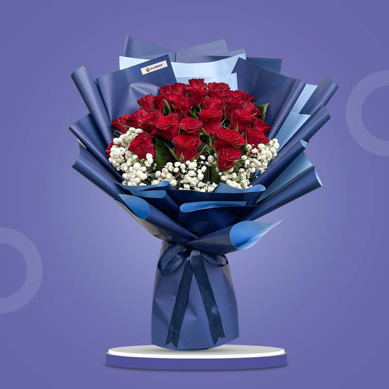 Amethyst Flora bouquet with 30 red China roses and gypsophila baby’s breath in 2‑toned navy blue wrap tied with a navy blue ribbon