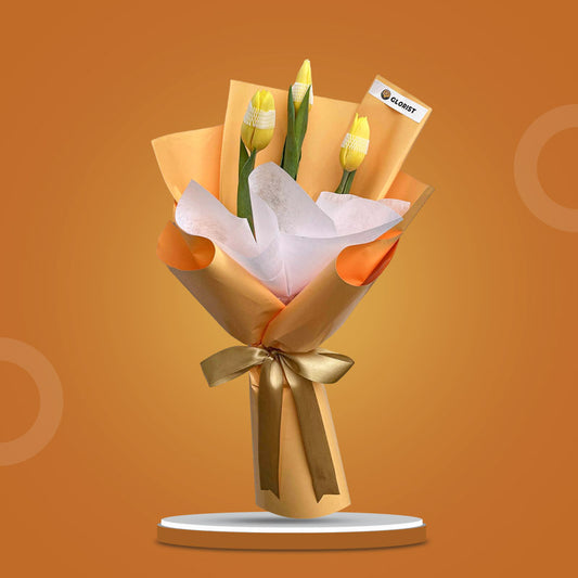 Authentic Perennial bouquet with three yellow tulips in yellow-orange and white wrap tied with light gold ribbon