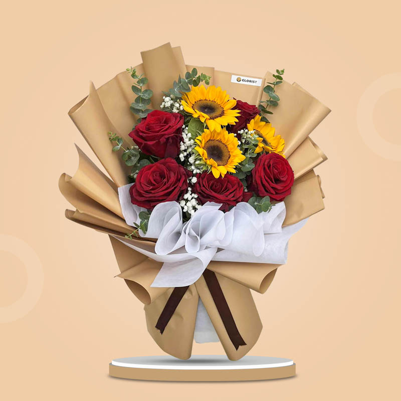 Blush Love bouquet with red Ecuadorian roses, sunflowers, eucalyptus, and baby’s breath in kraft Korean wrap and brown ribbon