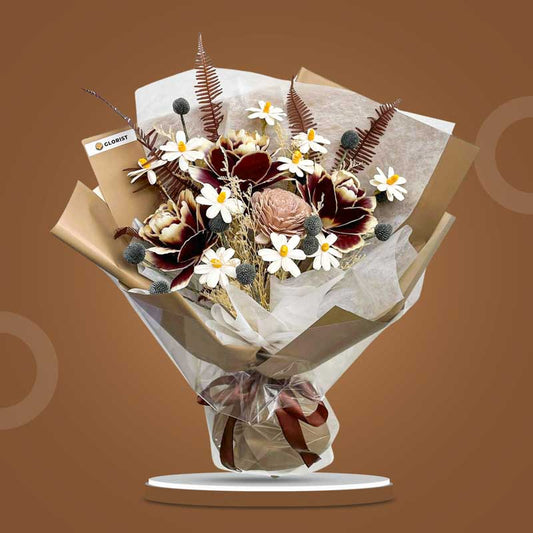 Calcite Timeless dried bouquet with dark maroon Asian peony, black craspedia, sola chrysanthemum, sola daisies, misty filler and skeletal fern in light cafe wrap with brown ribbon