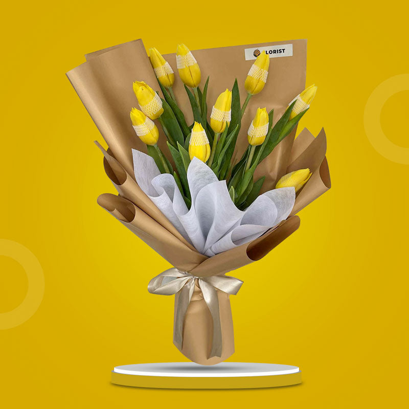 Fable Perennial bouquet with ten yellow tulips wrapped in kraft and white non-woven paper tied with a latte ribbon