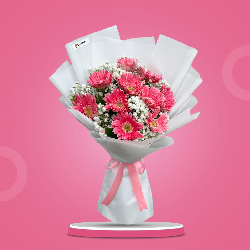 Faith Adoration bouquet with 10 light pink gerbera daisies and gypsophila baby’s breath wrapped in white paper with pink ribbon