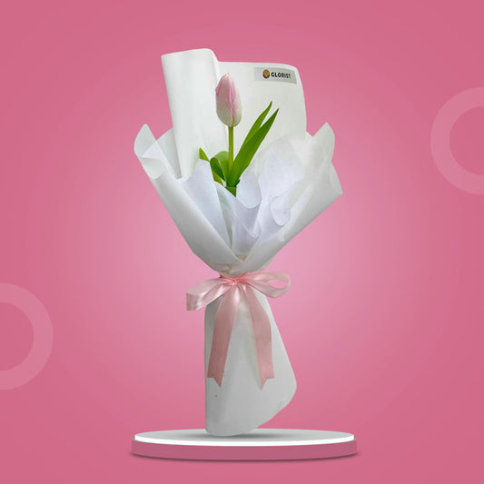 Fine Perennial bouquet with a light pink tulip in layered white Korean and non-woven wrap tied with a light pink ribbon