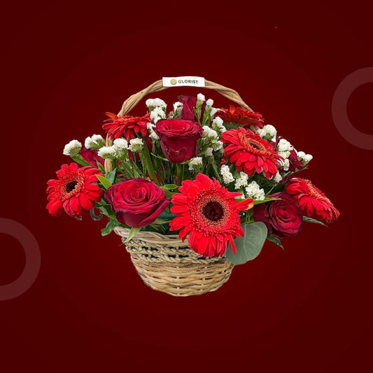 Flourish Fantasy basket with red gerbera daisies, red China roses, and white statice in a woven basket