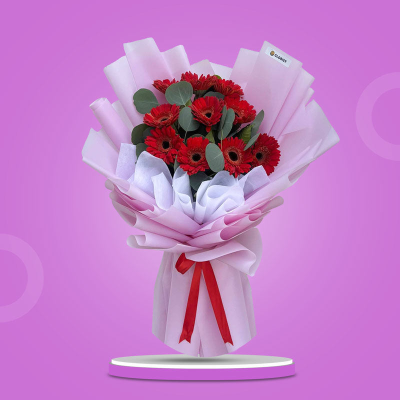 Genuine Adoration bouquet with 10 red Gerbera daisies and Eucalyptus Silver Dollar in light violet wrap with red ribbon