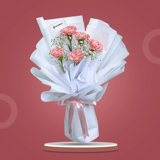 Harmony Radiance bouquet with light pink carnations and baby’s breath wrapped in white Korean paper and pink ribbon