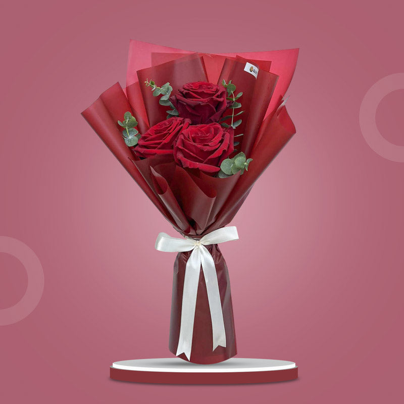 Luna Dreamland bouquet with 3 red Ecuadorian roses and eucalyptus baby blue in maroon wrap tied with a cream ribbon