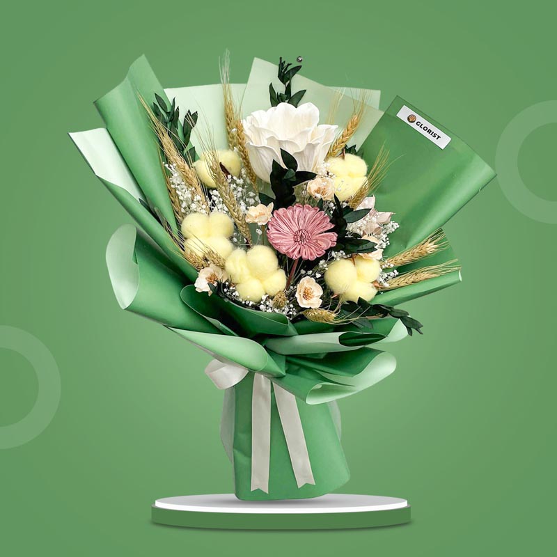 Malachite Timeless dried bouquet with white sola peony, wheat ears, yellow cotton heads, primrose, bleached gypsophila, lotus wooden and gerbera wooden in dark green wrap with cream ribbon