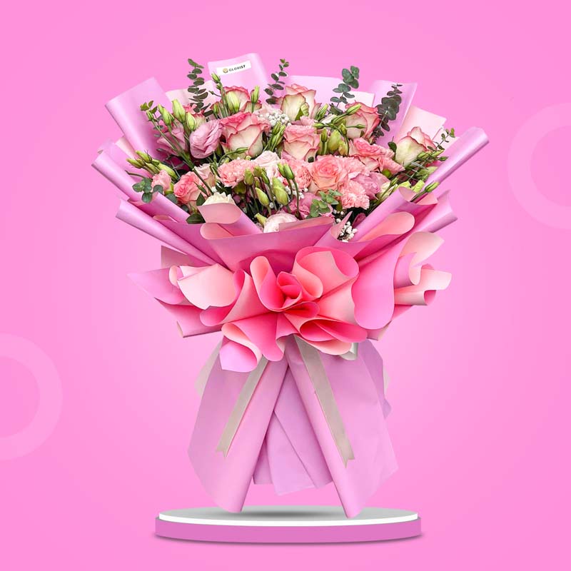 Oasis Love bouquet with 2-toned pink roses, carnations, lisianthus, eucalyptus, and baby’s breath in light pink wrap with cream ribbon