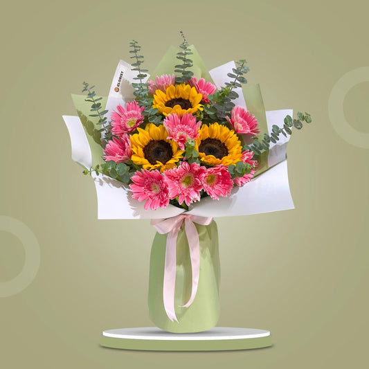 Rare Love bouquet with sunflowers, light pink gerbera daisies, and eucalyptus wrapped in matcha and white Korean paper with dark olive and pink ribbons