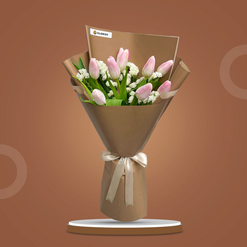 Stylish Perennial bouquet with nine light pink tulips and white statice in two-toned light café wrap tied with a latte ribbon
