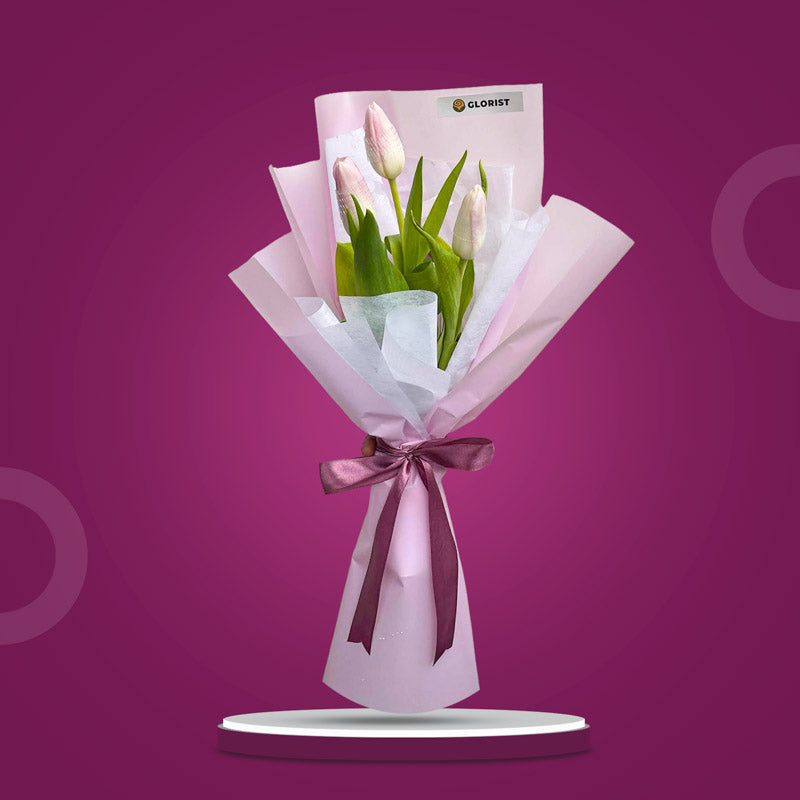 Treasured Perennial bouquet with three light pink tulips in light violet and white wraps tied with an old rose ribbon