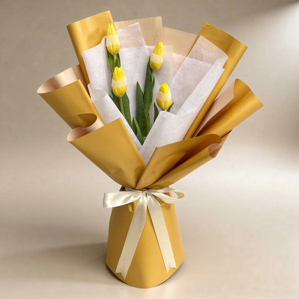 Worthy Perennial bouquet with four yellow tulips in mustard and white wraps tied with a cream ribbon