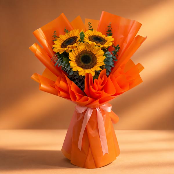 Zestful Summer bouquet with three sunflowers and eucalyptus in orange Korean wrap tied with salmon ribbon