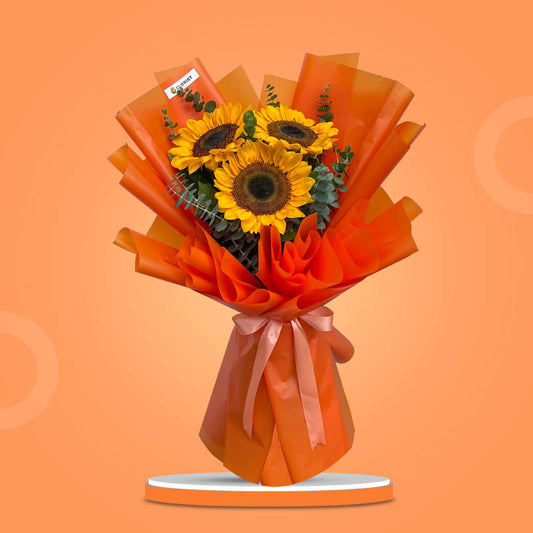 Zestful Summer bouquet with three sunflowers and eucalyptus in orange Korean wrap tied with salmon ribbon