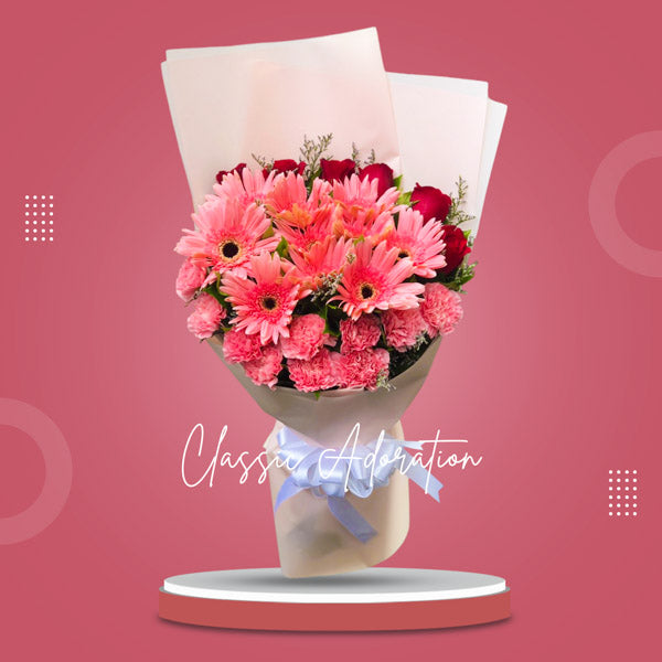 Stunning floral arrangement featuring light pink gerberas, carnations, red roses, and misty blue fillers in a Korean wrap. Enhanced with satin ribbon for an elegant touch. Perfect for weddings, special occasions, and gifts.