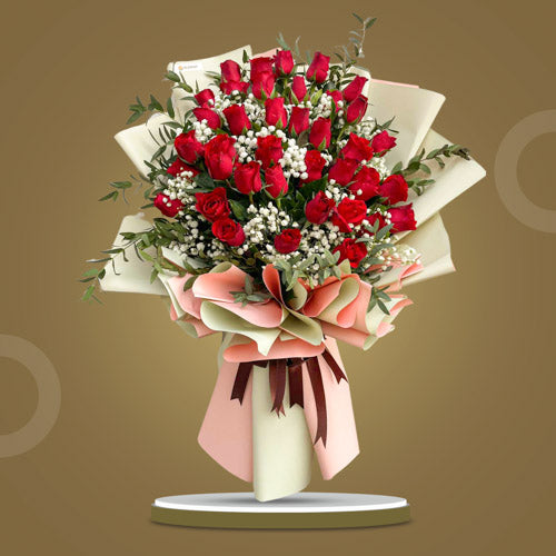 Affectionate Dreams bouquet featuring 36 red roses, lush Rosal leaves, and Gypsophila Baby's Breath, wrapped in pink gold Korean film with a wine red satin ribbon.