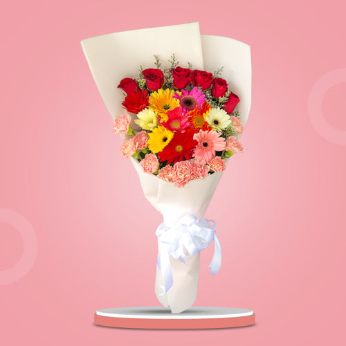 Stunning floral arrangement featuring 10 multi-colored gerberas, 10 carnations, 6 red roses, and misty blue fillers in white Korean wrap with white satin ribbon - elegant flower arrangement for weddings and special occasions - flower delivery to SM City San Pablo and SM City Taytay