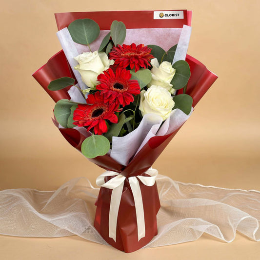 Abundant Love bouquet with red gerberas, white roses, and eucalyptus in maroon and white wrap with cream ribbon
