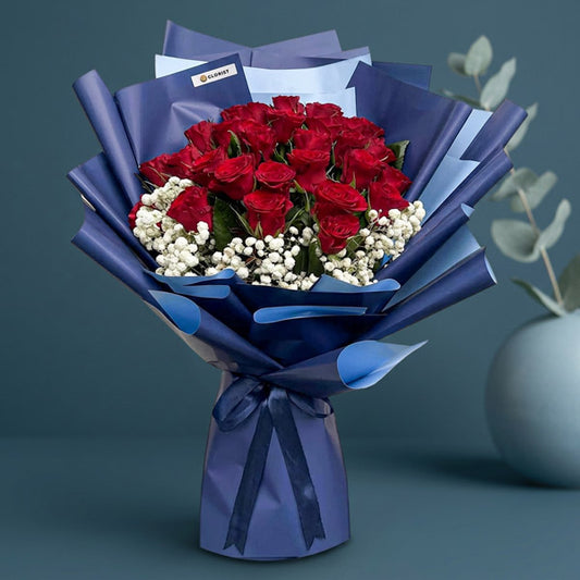 Amethyst Flora bouquet with 30 red China roses and gypsophila baby’s breath in 2‑toned navy blue wrap tied with a navy blue ribbon