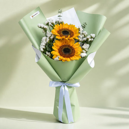 Attractive Summer bouquet with two sunflowers, eucalyptus baby blue, and statice in matcha green wrap with white ribbon
