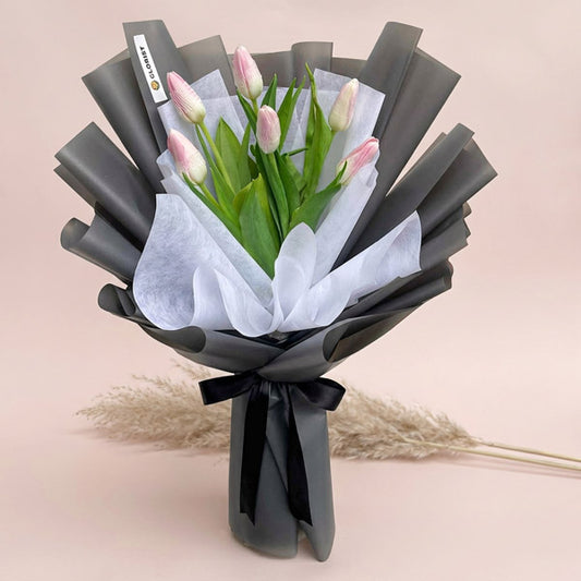 Chic Perennial bouquet with six light pink tulips in dark gray and white wraps tied with black ribbon