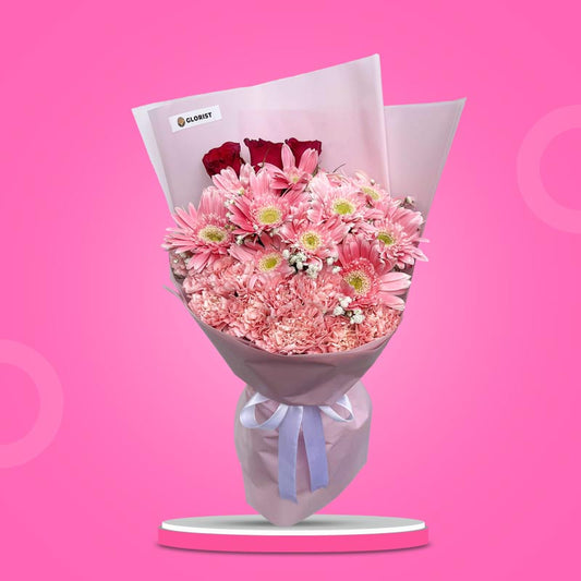 Classic Love bouquet with red China roses, light pink gerbera daisies, pink carnations, baby’s breath, pink wrap, and white ribbon