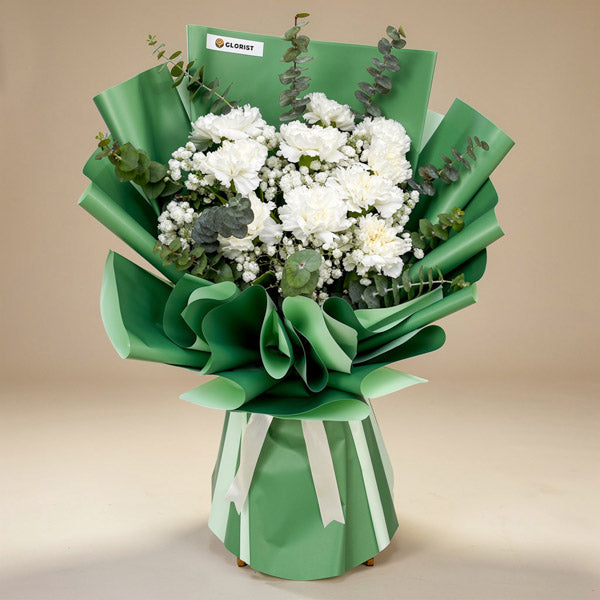 Elite Radiance bouquet with white carnations, eucalyptus, and baby’s breath in green Korean wrap with cream ribbon