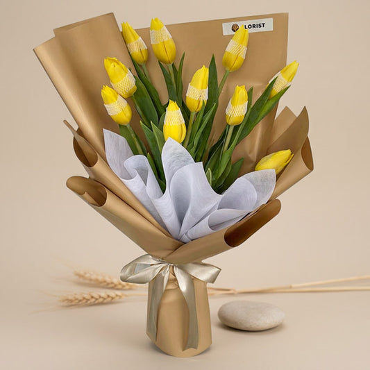 Fable Perennial bouquet with ten yellow tulips wrapped in kraft and white non-woven paper tied with a latte ribbon