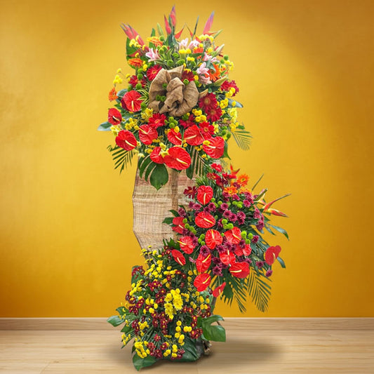 Fabulous Launch Inaugural Stand with red anthurium, gerbera daisies, stargazer lilies, jaguar flowers, bird-of-paradise, and green and yellow buttons