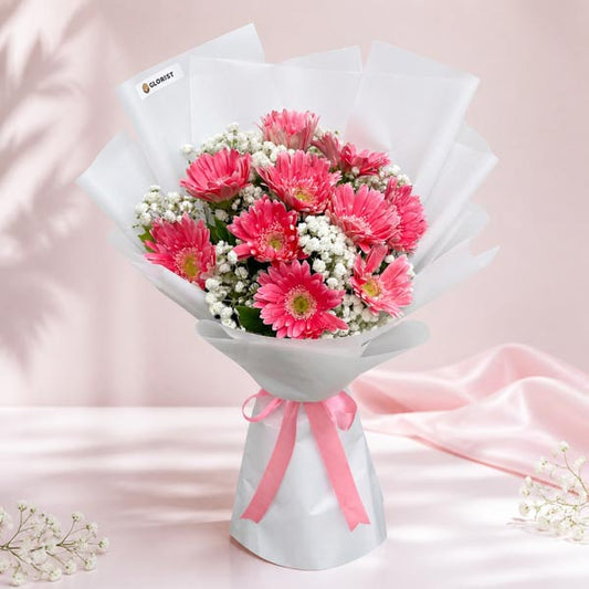 Faith Adoration bouquet with 10 light pink gerbera daisies and gypsophila baby’s breath wrapped in white paper with pink ribbon
