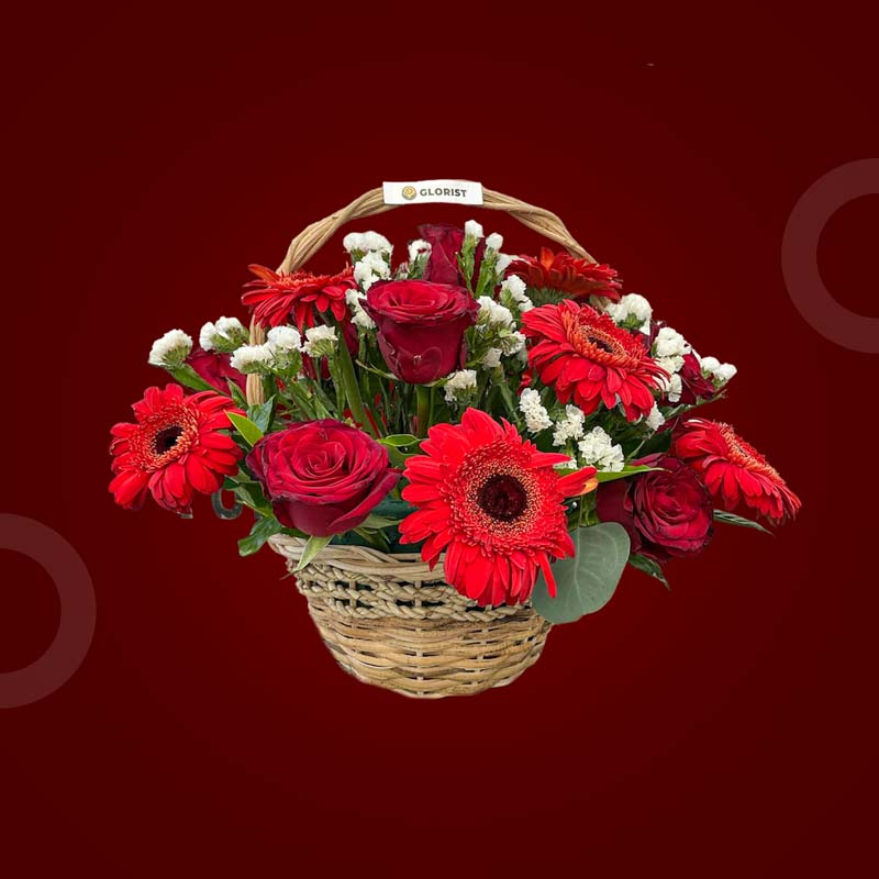 Flourish Fantasy basket with red gerbera daisies, red China roses, and white statice in a woven basket