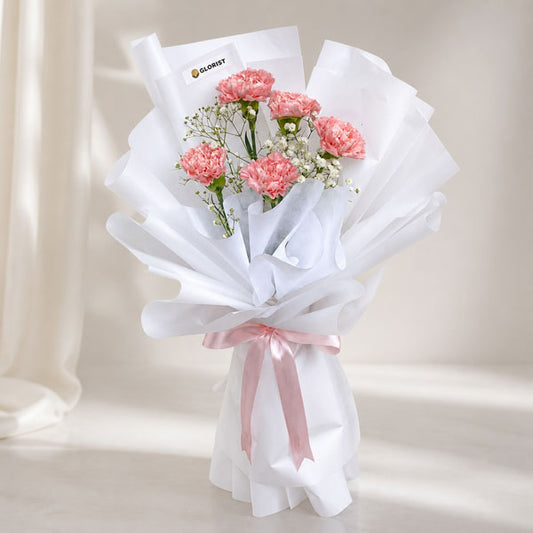 Harmony Radiance bouquet with light pink carnations and baby’s breath wrapped in white Korean paper and pink ribbon