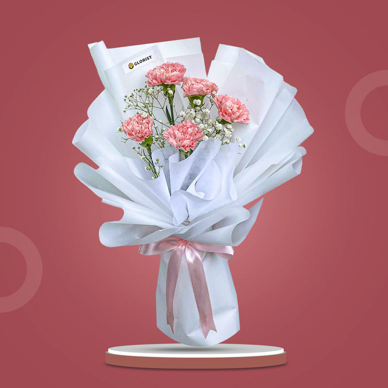 Harmony Radiance bouquet with light pink carnations and baby’s breath wrapped in white Korean paper and pink ribbon