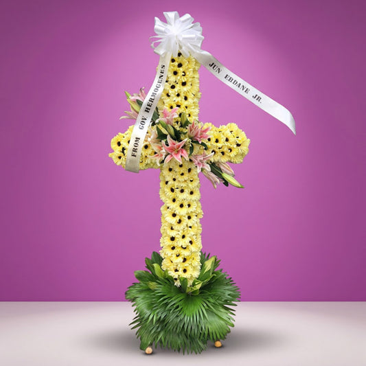 Life Memory Cross Stand with yellow gerbera daisies, stargazer lilies, and anahaw leaves