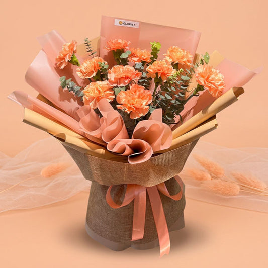 Orange carnation bouquet with eucalyptus fillers and peach ribbon