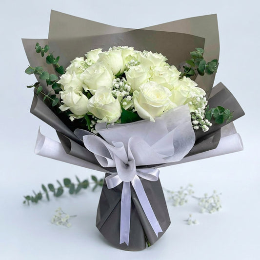 Resilient Flora bouquet with 20 white China roses, eucalyptus baby blue, and gypsophila baby’s breath in dark gray and white wrap tied with a white ribbon