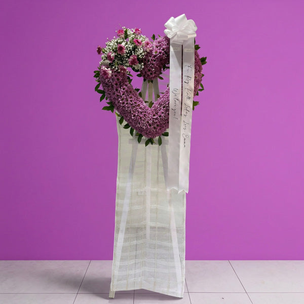 Purple mums and violet carnation in heart shape funeral flower stand arrangement