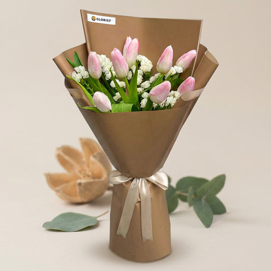 Stylish Perennial bouquet with nine light pink tulips and white statice in two-toned light café wrap tied with a latte ribbon