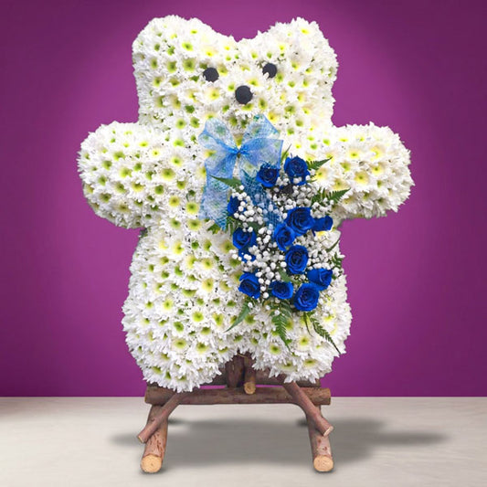 Funeral and sympathy flower stand with white Malaysian mums, red roses, and misty blue accents.