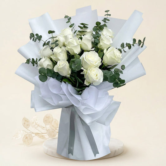 Willing Flora bouquet with 15 white China roses and eucalyptus baby blue in white Korean and non‑woven wrap tied with a silver ribbon