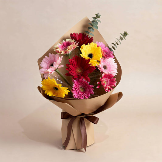 Witty Adoration bouquet with 10 assorted color gerbera daisies and eucalyptus Baby Blue, wrapped in kraft paper with brown ribbon — same-day delivery Manila