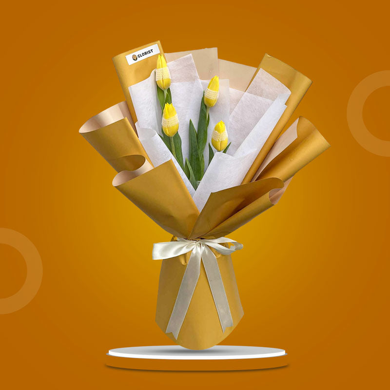 Worthy Perennial bouquet with four yellow tulips in mustard and white wraps tied with a cream ribbon