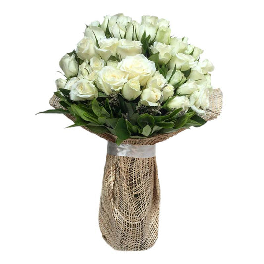 Beautiful vase filled with 36 white roses accompanied by delicate misty blue fillers, creating an elegant and enchanting floral arrangement.